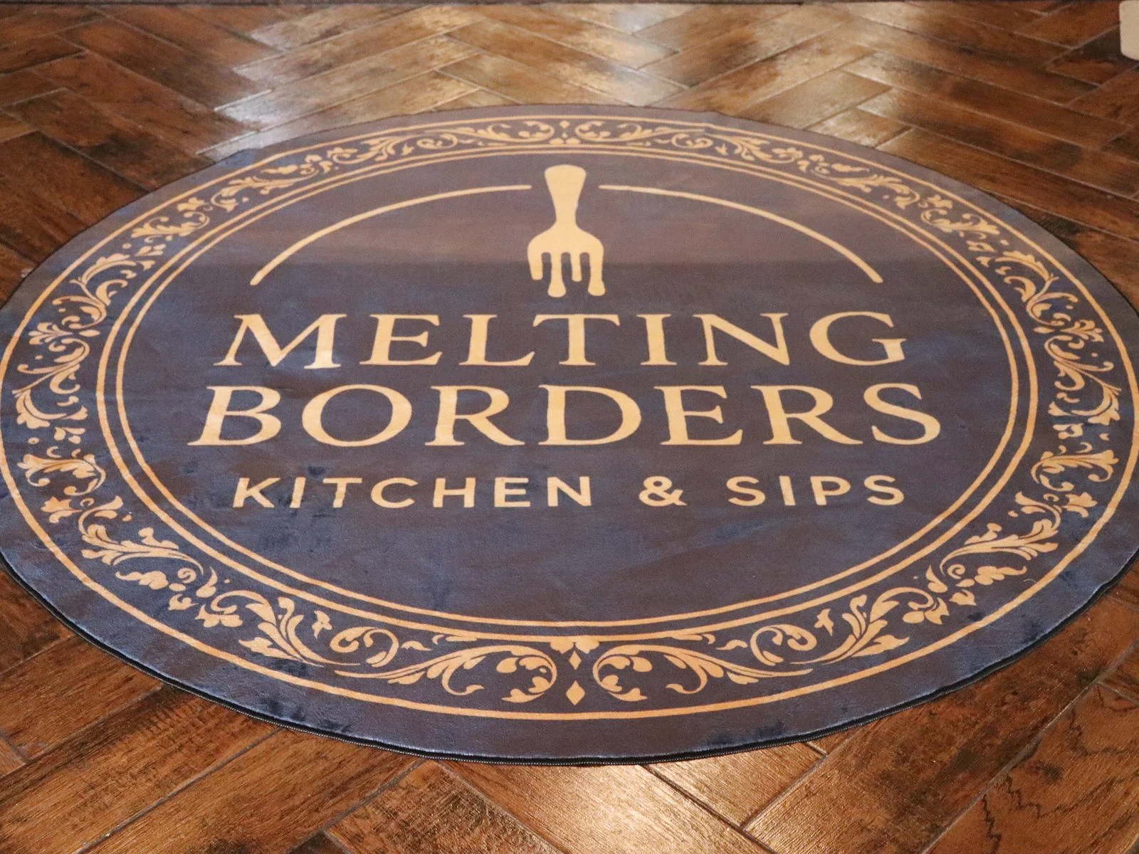 The Melting Borders logo rug at the entrance of the restaurant